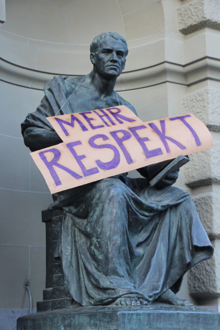 EKdM Kartonschild "Mehr Respekt" an Statue.